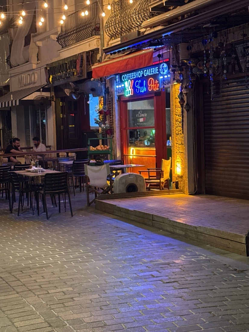 Gece vakti neon ışıklı cephe ve sokak masaları