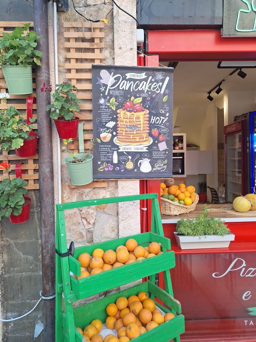 Kırmızı köşede 'Pancakes!' yazan kara tahta ve portakal dolu yeşil sehpa