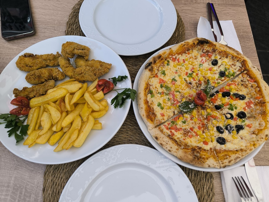 Çıtır tavuk, patates ve pizza ile donanmış masa