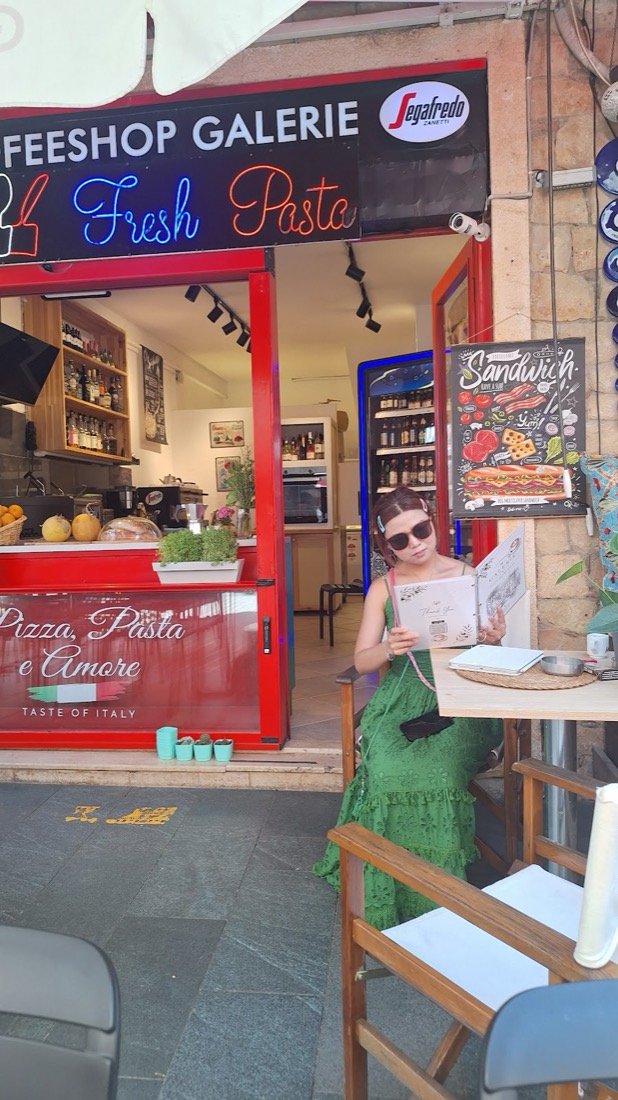 Coffee Shop Galerie'nin kırmızı vitrini önünde dergisini okuyan bir konuk